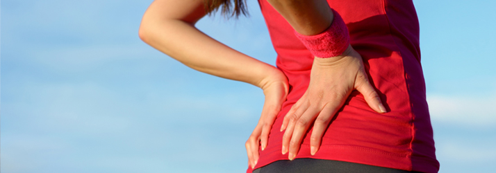 A person in sports clothing with both hands on their lower back