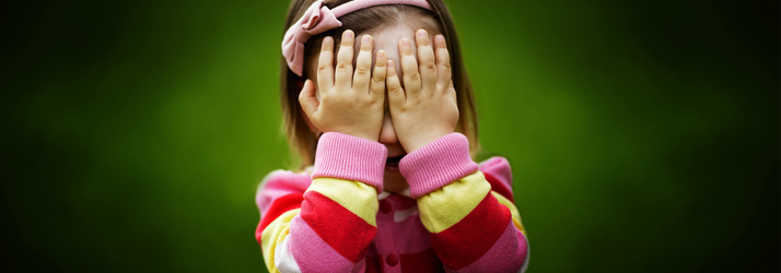 A child covering their face with both hands