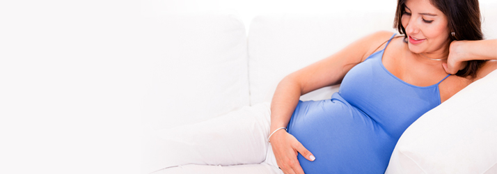 A pregnant woman reclining with a hand on her abdomen