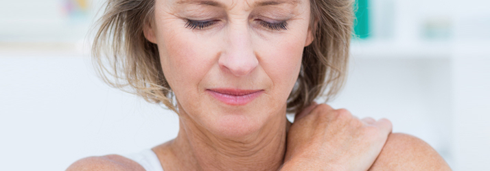 A woman resting one hand on her shoulder