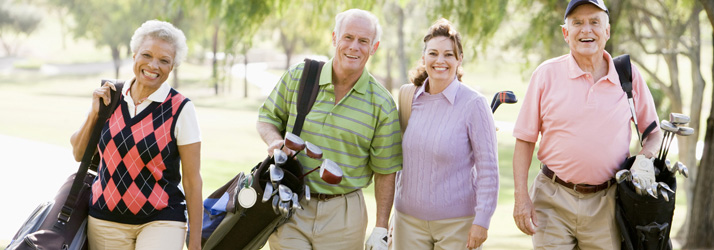 Four people walking with golf equipment