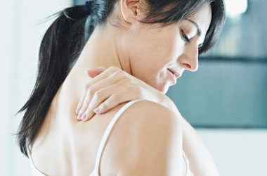 A woman resting her hand on the back of her shoulder