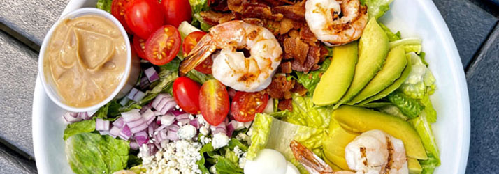 A salad with shrimp, avocado, tomatoes and egg