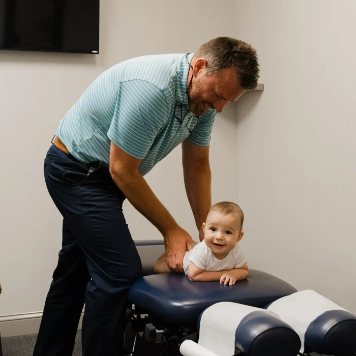 Dr. Jeff Morrey beside an infant on a treatment table